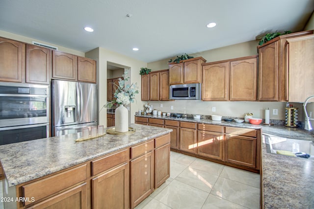 kitchen with a center island, light tile patterned floors, sink, and appliances with stainless steel finishes