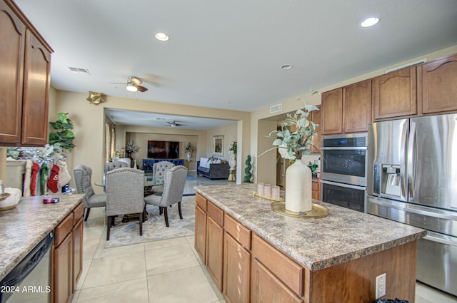 kitchen featuring light tile patterned floors, a center island, stainless steel appliances, and ceiling fan