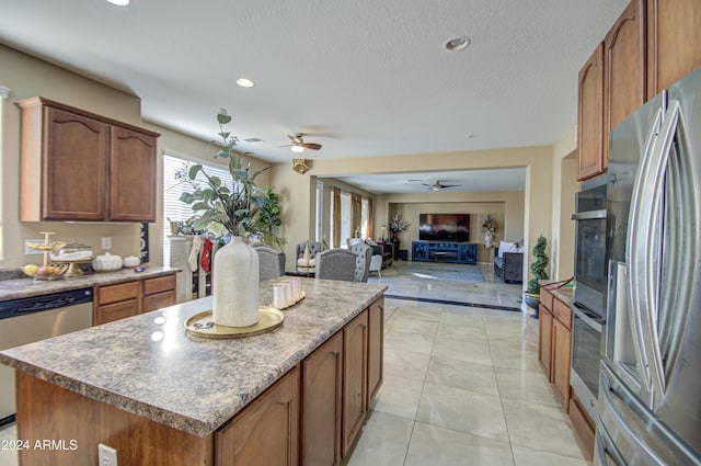 kitchen featuring a textured ceiling, stainless steel appliances, ceiling fan, light tile patterned floors, and a kitchen island