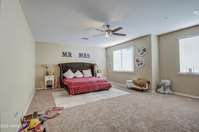 carpeted bedroom featuring ceiling fan and a textured ceiling