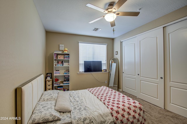 bedroom with ceiling fan, a closet, carpet floors, and a textured ceiling