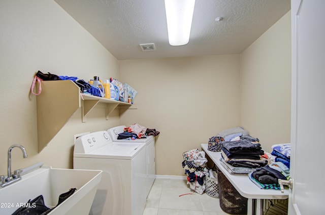 washroom with a textured ceiling, separate washer and dryer, and sink