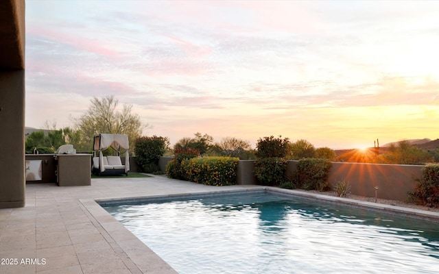 9894 E Miramonte Dr, Scottsdale, AZ 85262 - pool at dusk featuring exterior kitchen, a patio, and a fenced backyard