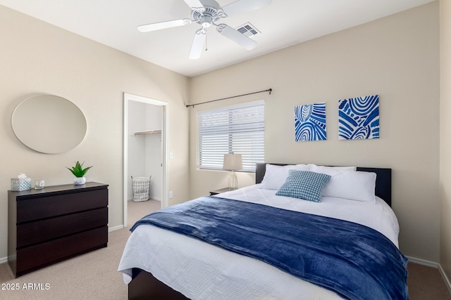 bedroom featuring a spacious closet, light carpet, ceiling fan, and a closet