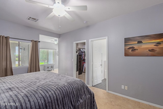 tiled bedroom featuring a spacious closet and ceiling fan