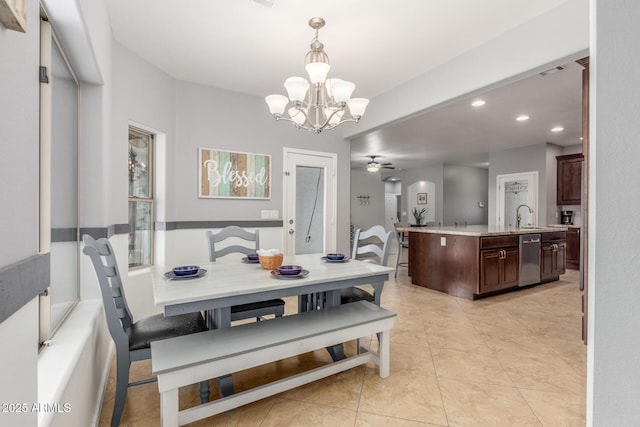 tiled dining area featuring sink and ceiling fan with notable chandelier