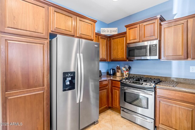 3932 E Melinda Dr, Phoenix, AZ 85050 - kitchen with dark stone countertops, light tile patterned floors, stainless steel appliances, and brown cabinetry
