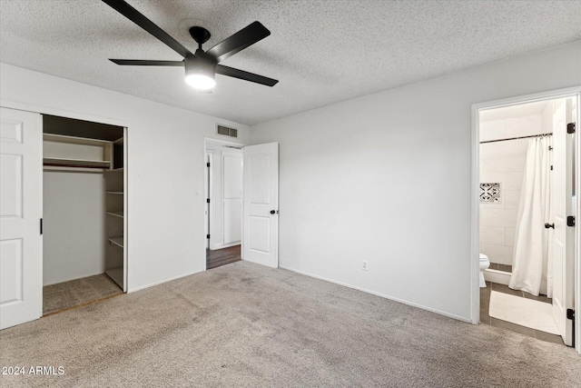 unfurnished bedroom featuring ensuite bath, a textured ceiling, ceiling fan, carpet floors, and a closet