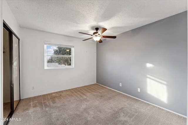 unfurnished bedroom with carpet flooring, ceiling fan, and a textured ceiling