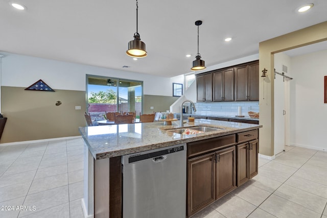 kitchen with light stone counters, decorative light fixtures, a center island with sink, stainless steel dishwasher, and sink