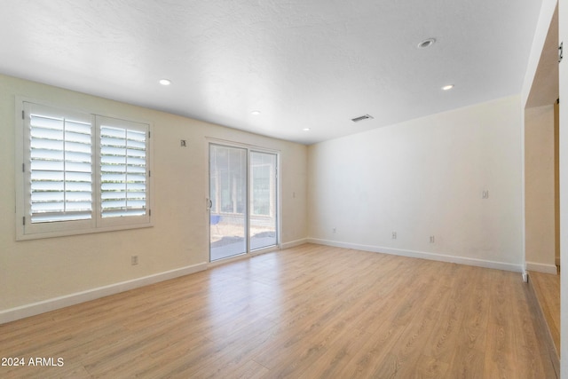 empty room featuring a textured ceiling and light hardwood / wood-style floors