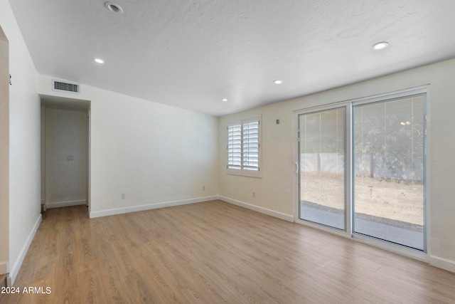 unfurnished room with a textured ceiling and light hardwood / wood-style flooring