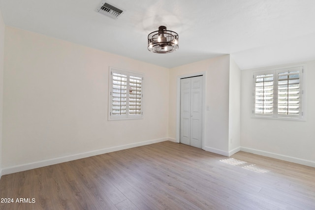 unfurnished bedroom featuring light hardwood / wood-style floors, a chandelier, and a closet