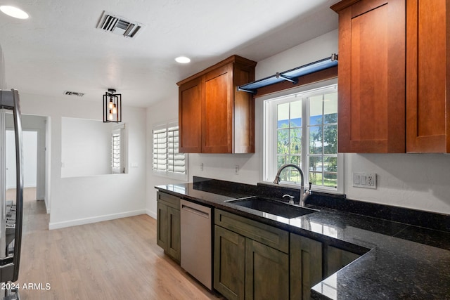 kitchen with dishwasher, pendant lighting, light hardwood / wood-style flooring, dark stone counters, and sink