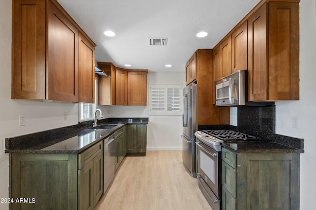 kitchen featuring dark stone counters, light hardwood / wood-style floors, sink, decorative backsplash, and stainless steel appliances