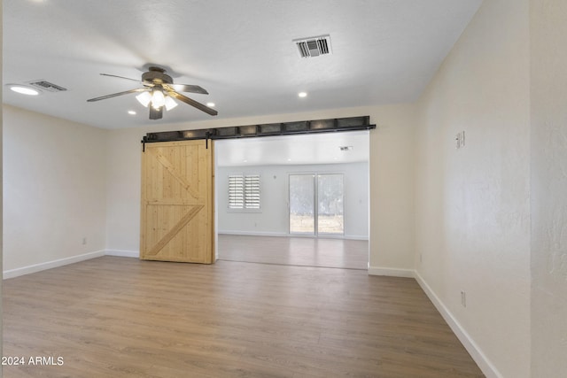 spare room featuring ceiling fan, hardwood / wood-style floors, and a barn door