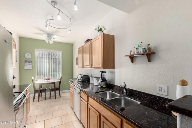 kitchen featuring appliances with stainless steel finishes, track lighting, dark stone counters, sink, and ceiling fan