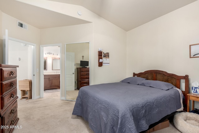 carpeted bedroom featuring lofted ceiling and ensuite bath