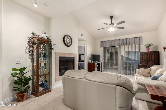 living room featuring a fireplace, ceiling fan, vaulted ceiling, and light colored carpet