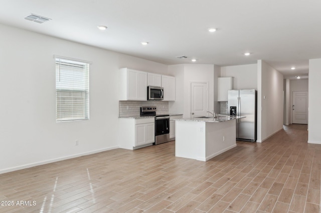 17806 W Vogel Ave, Waddell, AZ 85355 - kitchen with appliances with stainless steel finishes, a sink, backsplash, white cabinetry, and a kitchen island with sink