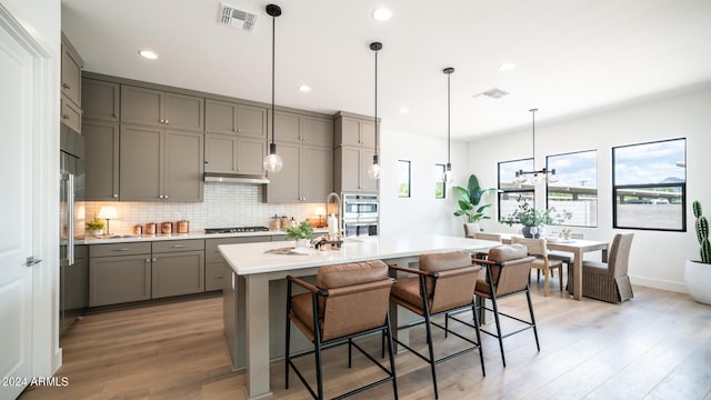 kitchen with a kitchen breakfast bar, gray cabinets, and light hardwood / wood-style flooring