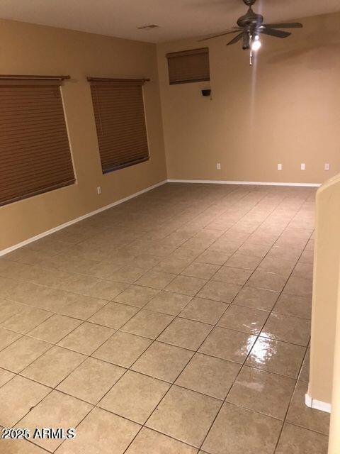 empty room with light tile patterned floors, baseboards, and a ceiling fan