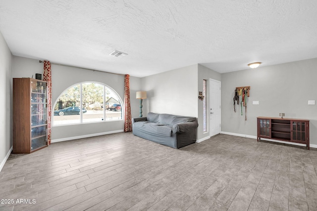 unfurnished living room with light hardwood / wood-style floors and a textured ceiling