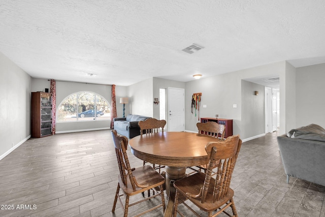 dining area featuring wood-type flooring and a textured ceiling