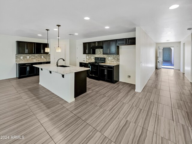 kitchen featuring a center island with sink, sink, tasteful backsplash, and black electric range