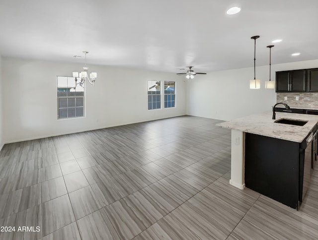 kitchen with hanging light fixtures, ceiling fan with notable chandelier, backsplash, sink, and light tile floors