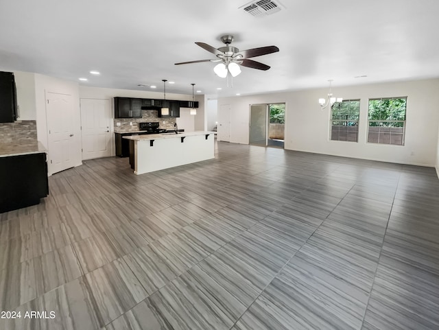 unfurnished living room featuring tile floors, ceiling fan with notable chandelier, and a healthy amount of sunlight