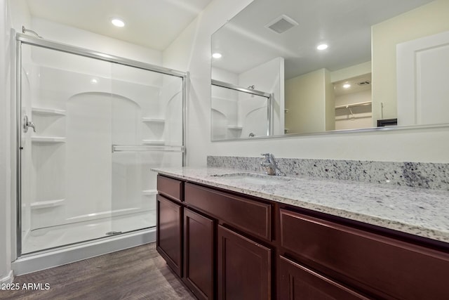 bathroom with walk in shower, vanity, and hardwood / wood-style floors