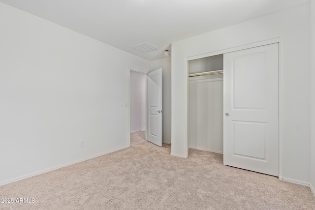 unfurnished bedroom featuring light carpet and a closet