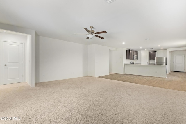 unfurnished living room featuring light carpet and ceiling fan