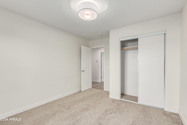 unfurnished bedroom with light carpet and a closet