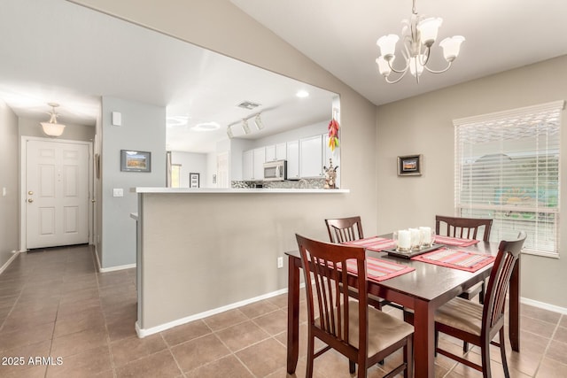 tiled dining area featuring vaulted ceiling and a notable chandelier