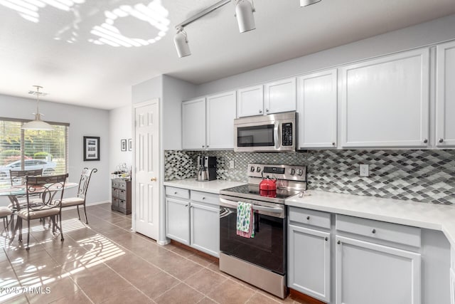 kitchen with light tile patterned floors, appliances with stainless steel finishes, pendant lighting, decorative backsplash, and white cabinets