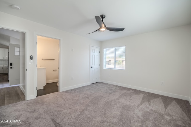 unfurnished bedroom featuring ceiling fan, a closet, ensuite bath, and dark colored carpet