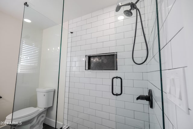 bathroom featuring toilet and a shower with door