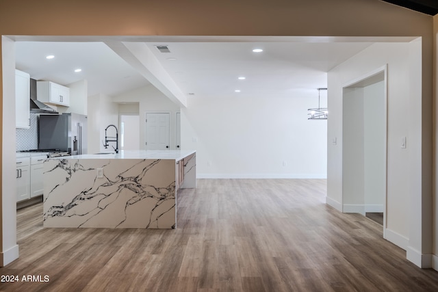 kitchen featuring light wood-type flooring, lofted ceiling, a kitchen island with sink, and white cabinets