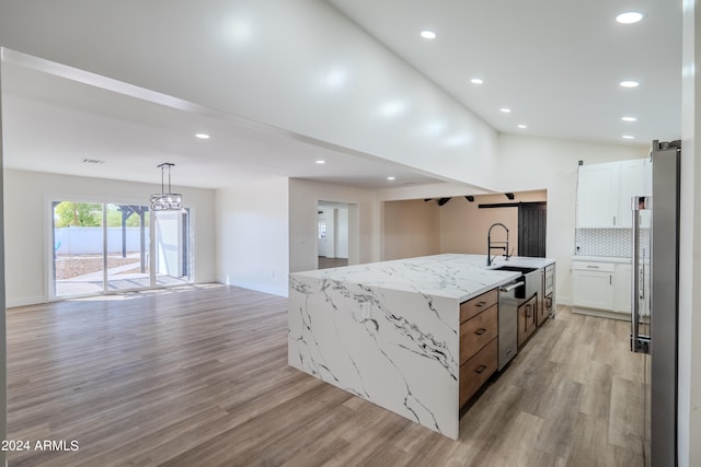 kitchen featuring white cabinetry, light stone counters, a barn door, light hardwood / wood-style flooring, and a kitchen island with sink