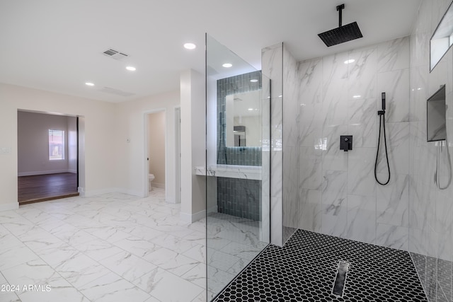 bathroom featuring a tile shower and toilet