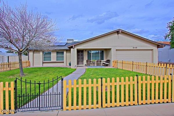 ranch-style house with a fenced front yard, a garage, solar panels, and a front yard