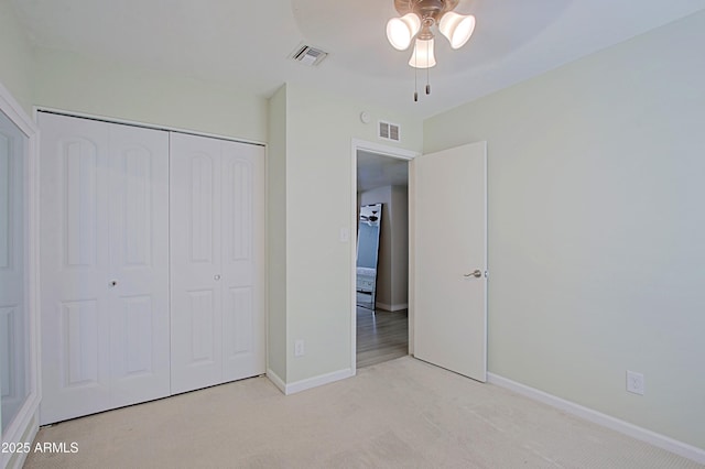 unfurnished bedroom with light colored carpet, visible vents, a closet, and baseboards