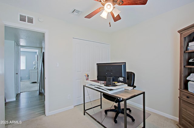 office space featuring a ceiling fan, visible vents, and baseboards