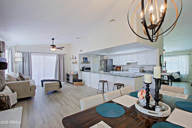 dining room featuring lofted ceiling, light wood-style flooring, ceiling fan with notable chandelier, and visible vents