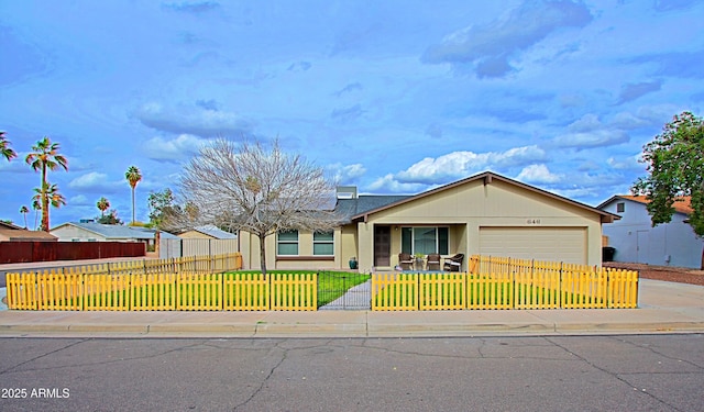 single story home with a fenced front yard, an attached garage, concrete driveway, and a front lawn