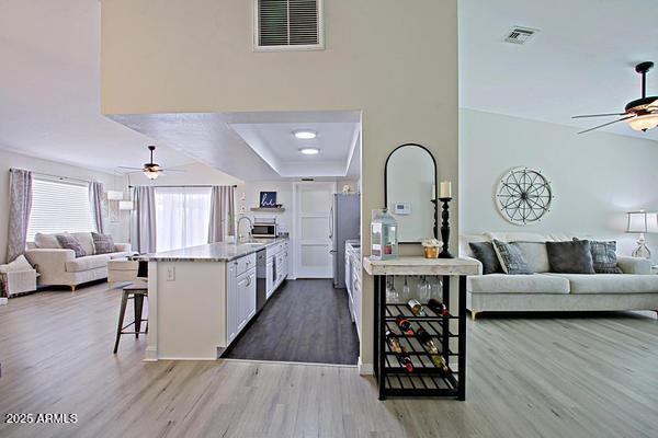 kitchen with open floor plan, visible vents, freestanding refrigerator, and ceiling fan