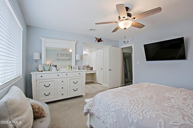 bedroom featuring ensuite bath, light colored carpet, visible vents, and ceiling fan