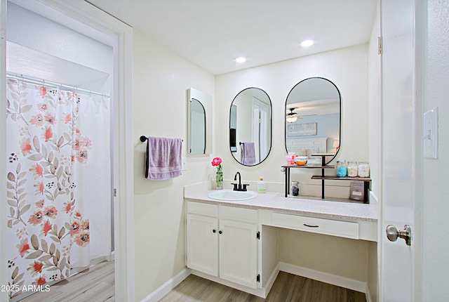 bathroom featuring baseboards, a ceiling fan, wood finished floors, and vanity